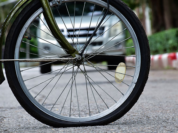 Close-up of a bicycle&rsquo;s rear wheel with a flat tire parked on a sidewalk beside the road, highlighting common bike hazards and evidence in New York City bicycle accident cases