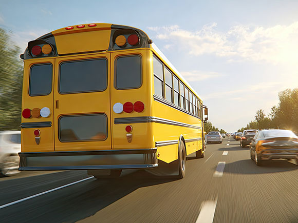 Yellow school bus driving along a highway, representing liability and injury claims handled by a New York City bus accident lawyer