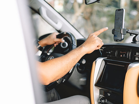 Driver using a mobile phone GPS navigation app while driving, illustrating rideshare app use and distracted driving risks in New York City Lyft accidents