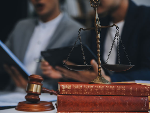 Lawyers meeting with a client in a law office beside a judge&rsquo;s gavel and scales of justice, representing a New York City premises liability lawyer consultation