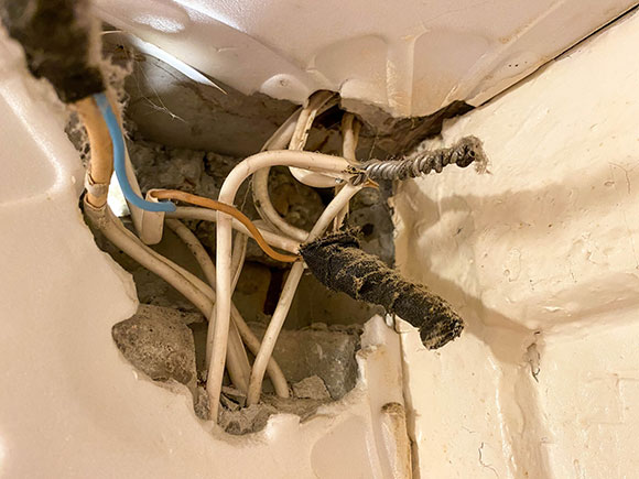 Exposed, tangled electrical wiring in a dusty wall cavity at a construction site, illustrating dangerous property conditions that can lead to New York City premises liability claims