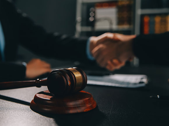 Business partners shaking hands while attorneys review contract documents in a meeting, representing legal guidance from a New York City rideshare accident lawyer after a crash