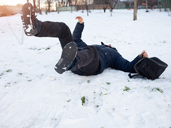 Man lying injured after slipping on an icy, snow-covered surface, illustrating winter sidewalk slip and fall accidents in New York City