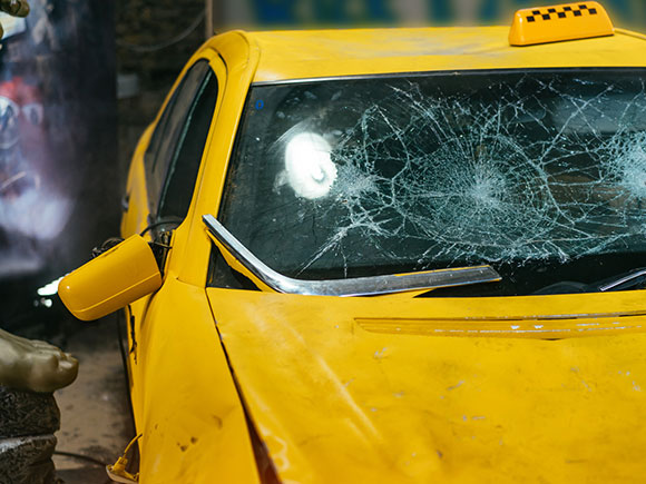 Close-up of cracked yellow car window glass after an accident, showing common damage evidence in New York City taxi accident claims
