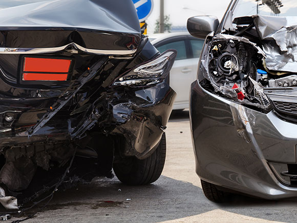 Damaged vehicles at the scene of a two-car accident, showing major impact to the rear and front ends.