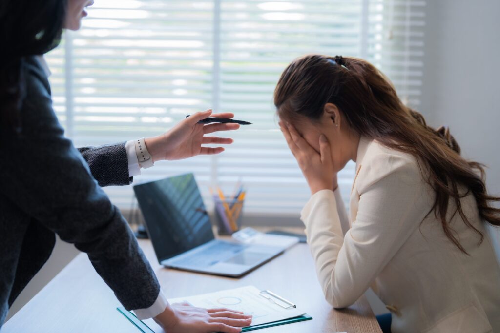 Employee in distress during a confrontation with a supervisor, highlighting the need for a New York City employment lawyer to address workplace harassment.