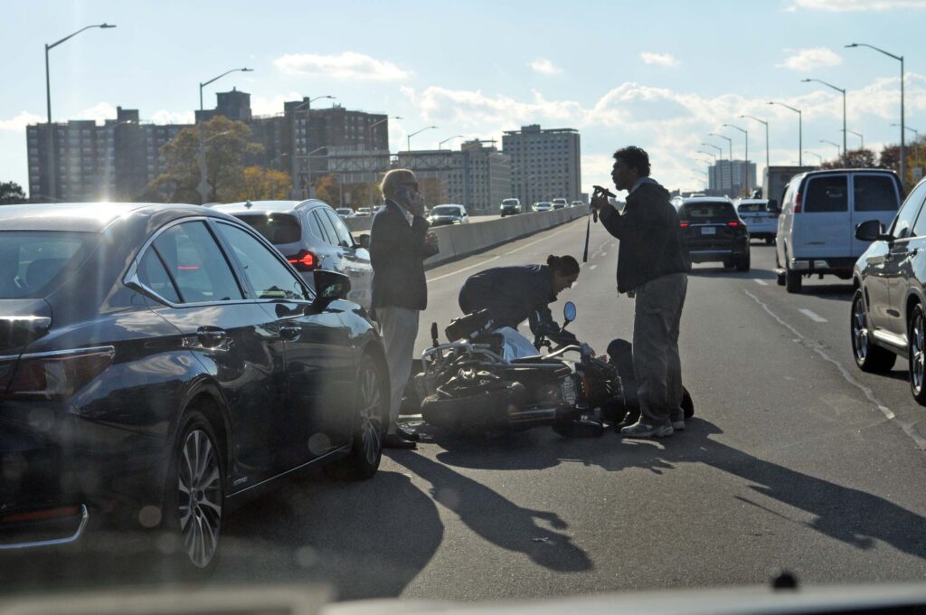 A downed motorcycle on a busy Nueva York highway after a collision, illustrating the high-stakes recovery cases handled by a New York City motorcycle accident lawyer.