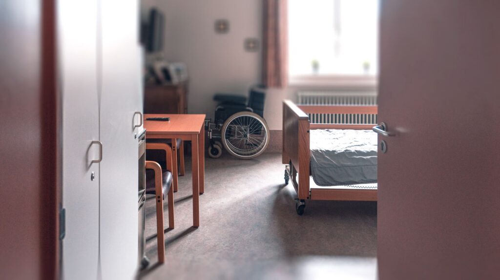 Empty nursing home room with a wheelchair in New York City, illustrating the potential for isolation and neglect in long-term care facilities.