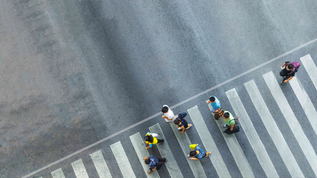 Aerial view of pedestrians using a crosswalk in New York City, where a negligent driver can cause life-altering injuries.