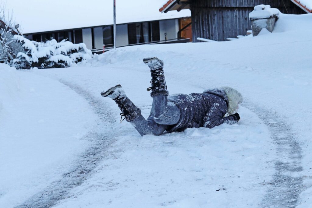 Pedestrian fallen on a snowy New York City path, requiring a trial-ready lawyer to investigate driver negligence and poor road conditions.