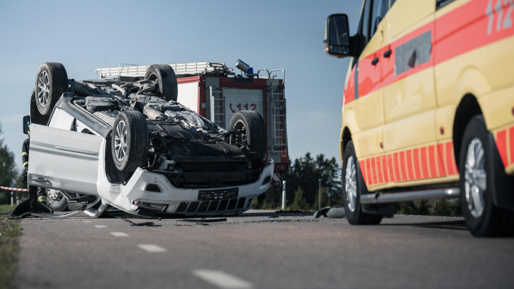 Overturned white vehicle on a New York City highway next to an emergency response van, documenting the catastrophic results of a commercial vehicle collision handled by a New York City truck accident lawyer.