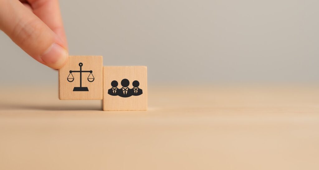 Wooden blocks with justice scales and a group of people, representing legal safeguards provided by a New York City whistleblower protection lawyer.