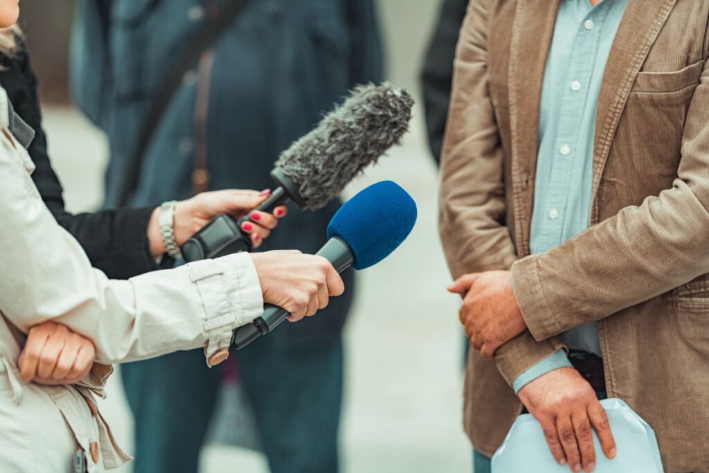 Reporter holding a microphone during an interview, illustrating the public exposure of fraud and misconduct addressed by a New York City whistleblower protection lawyer.