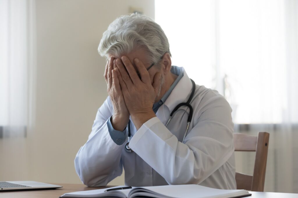 A doctor in New York City sitting with head in hands, symbolizing the devastating impact of fatal errors that lead families to seek a New York City wrongful death lawyer.