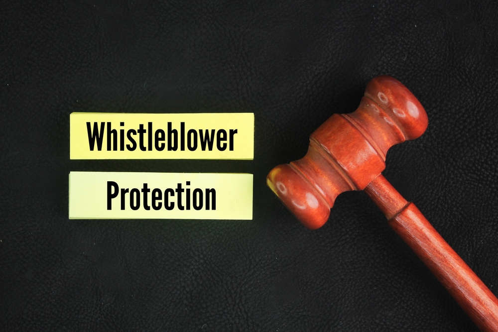 Judge's gavel and colored paper with the words whistleblower protection. concept of layer or offense case in court. Legal Shield and Justice