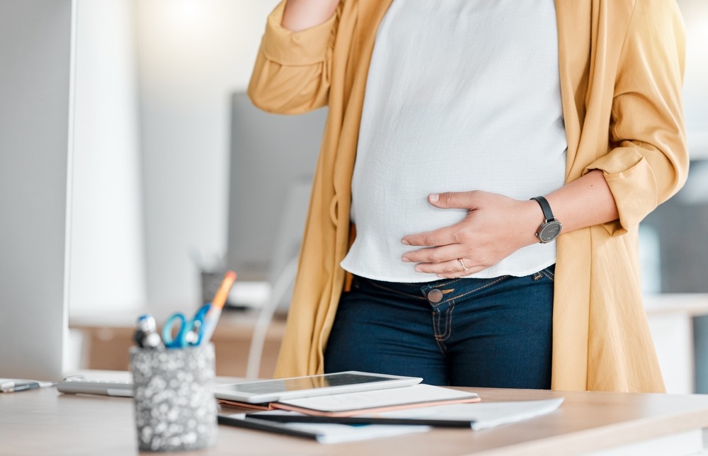 Sacramento pregnancy discrimination lawyer concept showing pregnant employee standing at her office workspace