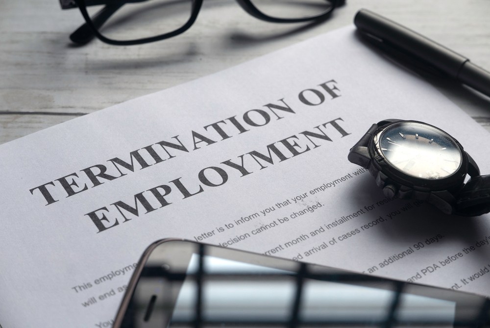 Termination of employment letter on desk with glasses, pen, and watch
